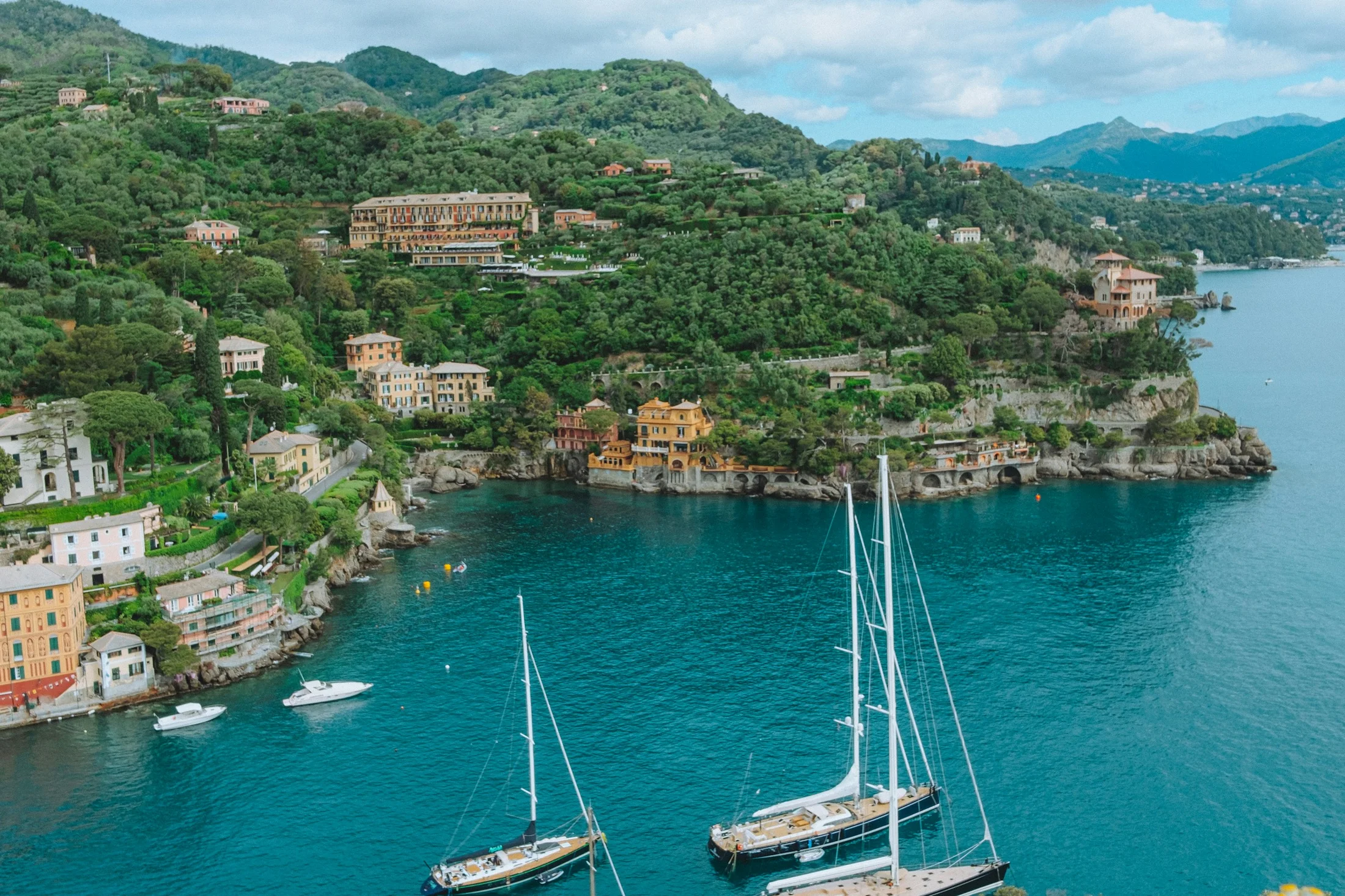 Sailing boats off the wooded Portofino coast in Liguria